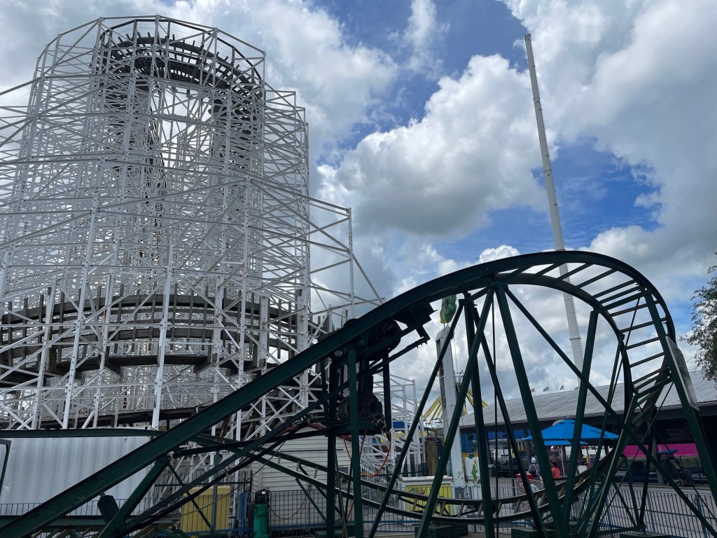 A kids roller coaster in front of a larger roller coaster and a sky coaster